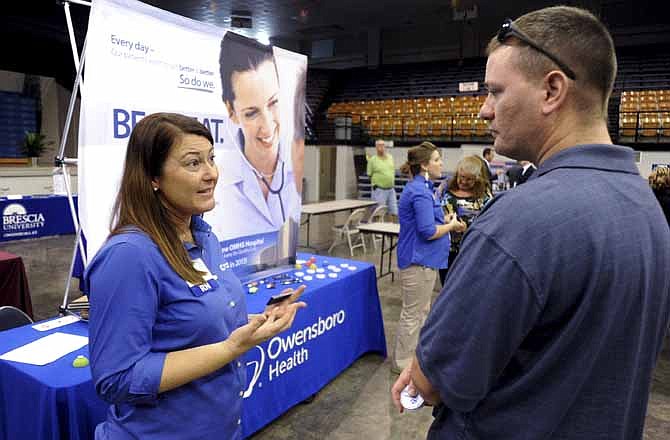 In this Oct. 1, 2013 photo, registered nurse Salanda Bowman, left, talks with part-time Kentucky Wesleyan College student Jason Ward, of Whitesville, about job openings at the Owensboro Health Regional Hospital during a Regional Career and Job Fair in the Owensboro Sports Center in Owensboro, Ky.