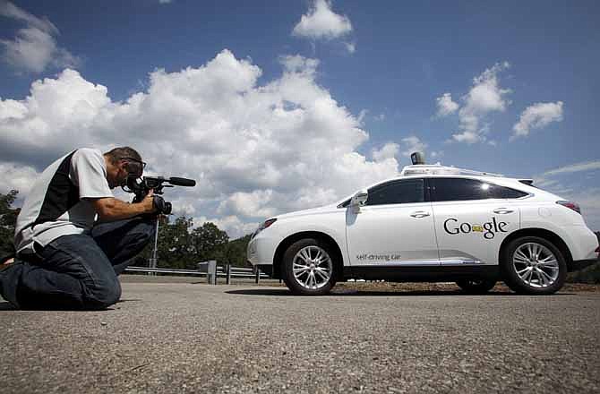 This Sept. 3, 2013, file photo shows a videographer photographing the Google self-driving car during a news conference at the Virginia Tech Transportation Institute's Smart Road in Blacksburg Va. 