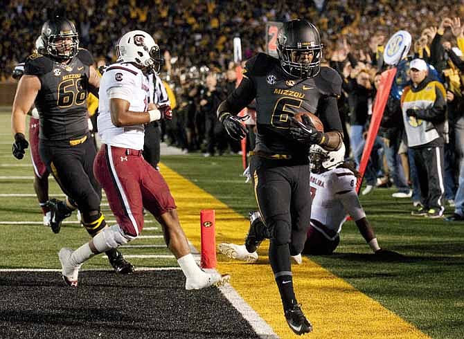 Missouri's Marcus Murphy, right, scores a touchdown in front of South Carolina's T.J. Holloman, center, and Missouri's Justin Britt (68) during the first quarter of an NCAA college football game Saturday, Oct. 26, 2013, in Columbia, Mo.