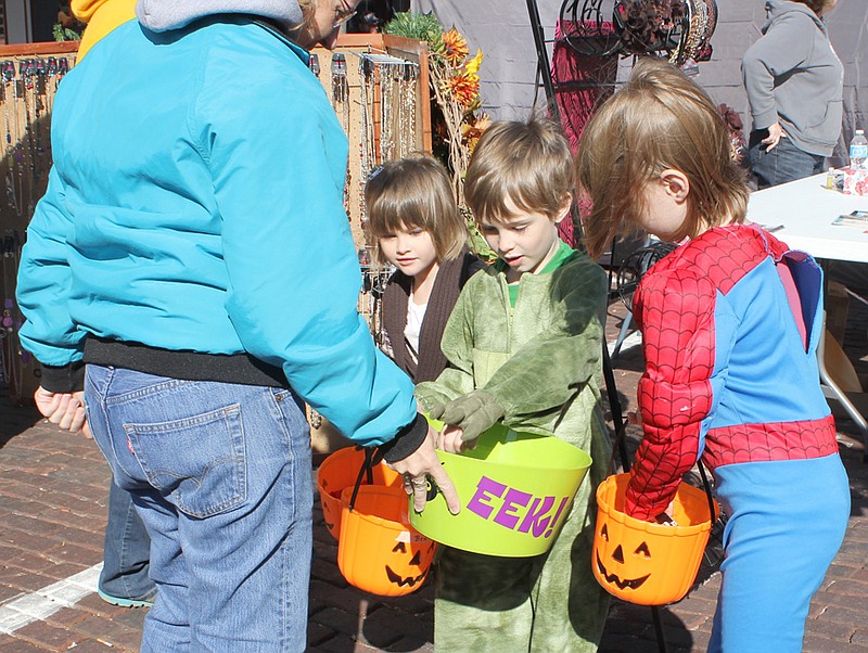 Catie, Ben and Anna Markway get candy while trick-or-treating their way through the vendors on Court Street during the Brick District Association's Harvest Festival Saturday morning. See today's edition for more festival photos.