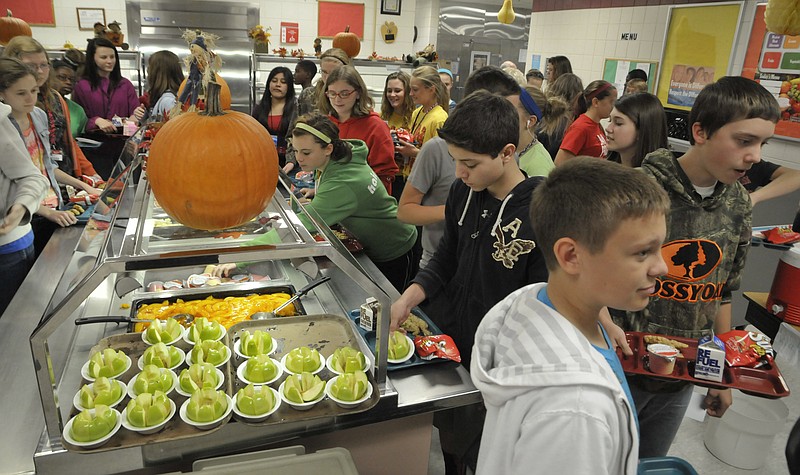 Students line up to make their selections and pay as lunch is served at Lewis & Clark Middle School. Inset at top, labels along the serving line encourage students to add fruit and vegetables to their meals. It's healthy for the students and the school's buget.