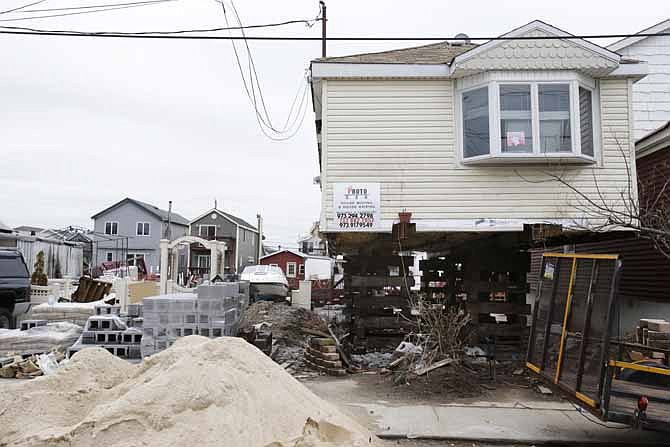 In this April 11, 2013, file photo, a home in the process of being raised is seen in the Broad Channel section of Queens, New York. A bipartisan group of House members and senators is pressing legislation to delay for four years changes to the federal government's flood insurance program that are threatening to sock thousands of people with unaffordable premium hikes.
