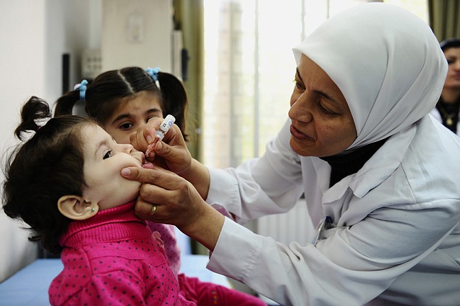 A health worker administers polio vaccine to a child as part of a UNICEF-supported vaccination campaign at the Abou Dhar Al Ghifari Primary Health Care Center in Damascus, Syria. The U.N.'s health agency said Tuesday it has confirmed 10 polio cases in northeast Syria, the first confirmed outbreak of the diseases in the country in 14 years, with a risk of spreading across the region.