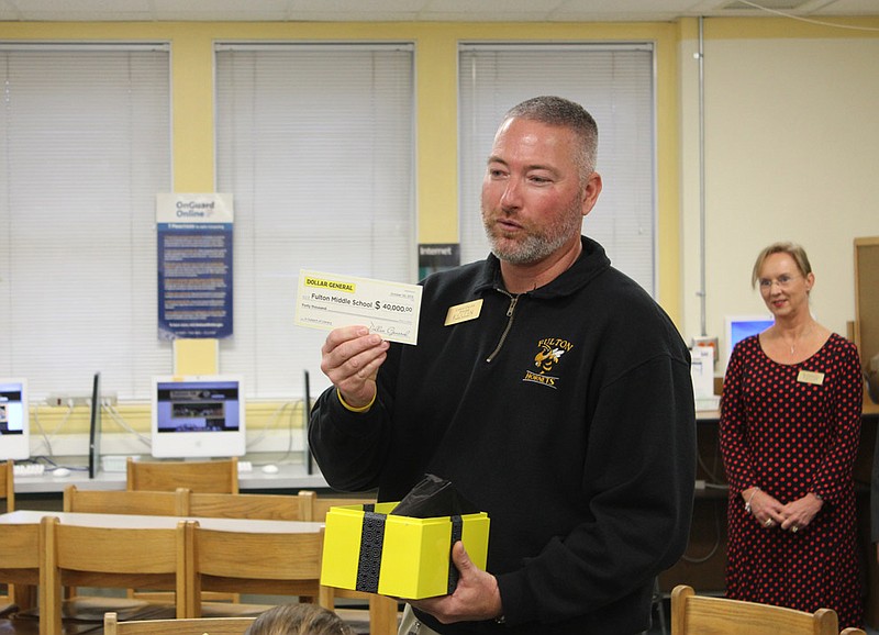 Fulton Middle School Principal Chris Crane shows off the $40,000 check presented by Fulton Dollar General Distribution Center Director Steve Gibson (not pictured) today in the middle school library.