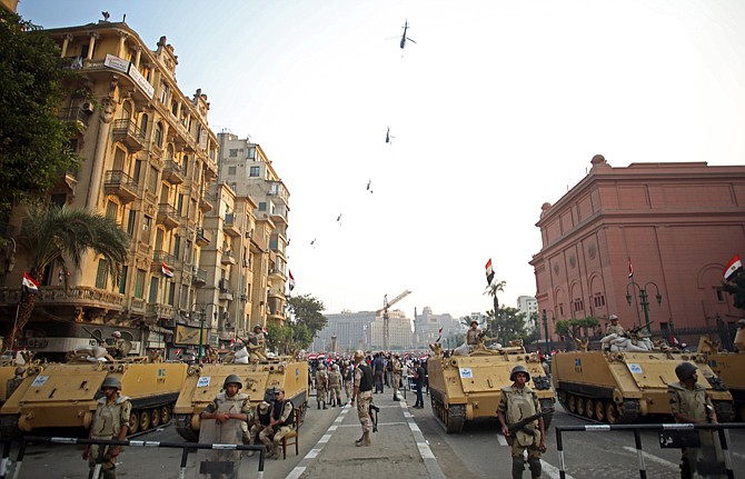 Egyptian military helicopters fly overhead as army soldiers stand guard at an entrance to Tahrir Square, in Cairo, Egypt. Under President Mohammed Morsi, his Islamist allies pushed through a constitution that alarmed many Egyptians with its new, stronger provisions for implementing Islamic Shariah law and carving out extensive power for the military.