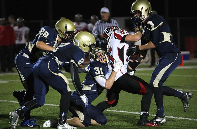 Helias defenders (from left) J.C. Szumigala, Josh Woodruff, Jordan Kemple and Weston Porter take down Marshall running back Devin Cott during the second half Thursday night at Adkins Stadium.