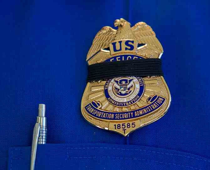 A Transportation Security Administration employee wears a black ribbon over his badge on Saturday, Nov. 2, 2013, in Los Angeles International Airport. A gunman armed with a semi-automatic rifle opened fire at the airport on Friday, killing a Transportation Security Administration employee and wounding two other people in an attack that frightened passengers and disrupted flights nationwide. 