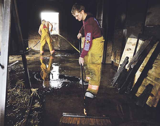 Cole County firefighters Jimmy Buechter, right, and Aaron Hood, left, sweep the straw, ash and water covered floor of the Jefferson City Hyde Park Fire Training Facility's burn room as they and fellow firefighters clean up the facility following the conclusion of Cole County Fire Districts' basic firefighter class on Saturday. 