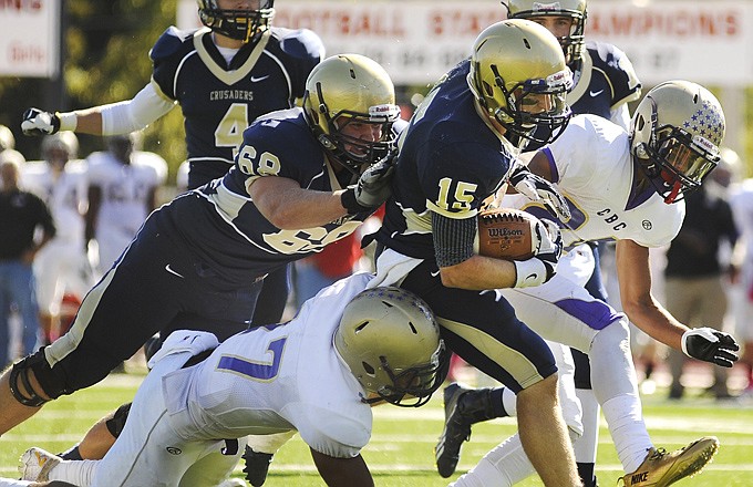 With the help of Tryston Bax (68), Helias running back Garrett Buschjost breaks through a pair of would-be C.B.C. tacklers on his way to the end zone during a game this season at Adkins Stadium.