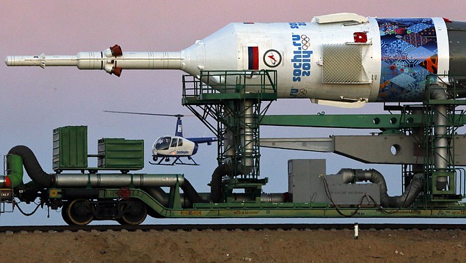 A Russian police helicopter guards the Russia's booster rocket Soyuz-FG with the space capsule Soyuz TMA-11M that will carry new crew to the International Space Station (ISS) as well as carry an Olympic torch to space as part of the ongoing Olympic torch relay. The torch will be brought back along with the station's current crew. The rocket is scheduled to blast off on Thursday.