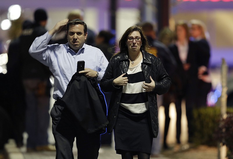 A man and woman leave the Garden State Plaza Mall with officials standing guard behind them Monday following reports of a shooter in Paramus, N.J. Hundreds of law enforcement officers converged on the mall Monday night after witnesses said multiple shots were fired there.