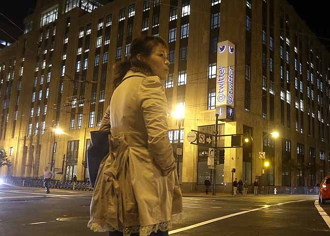 In this Monday, Nov. 4, 2013, photo, a woman stands across the street from Twitter headquarters in San Francisco. As Wall Street analysts size up Twitter ahead of its first public stock sale this week, more than a few are expressing concern about the company's lack of profits.