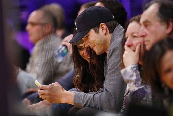 In this Feb. 12, 2013 file photo, actors Mila Kunis, left, and Ashton Kutcher, right, look at a mobile phone as they sit courtside together at the NBA basketball game between the Phoenix Suns and Los Angeles Lakers, in Los Angeles. Kutcher is included on a long list of celebrities who - at one time or another - have taken a break from Twitter. 