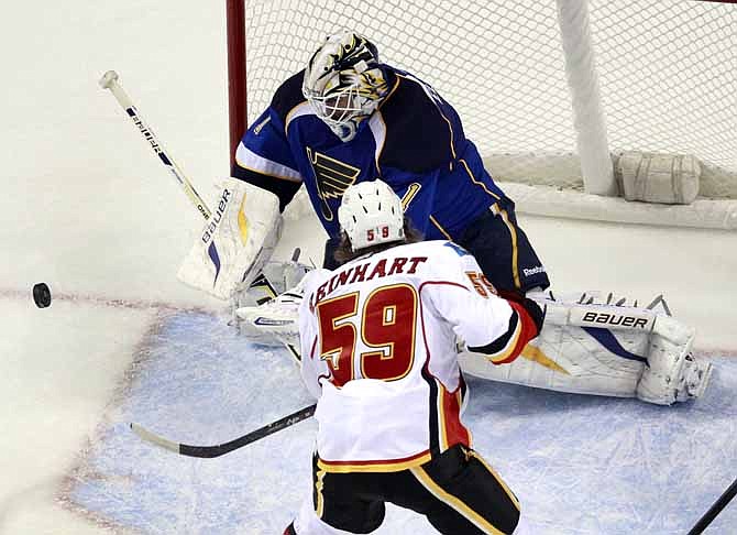 St. Louis Blues goalie Brian Elliott, top, deflects the puck as Calgary Flames' Max Reinhart watches during the second period of an NHL hockey game Thursday, Nov. 7, 2013, in St. Louis.