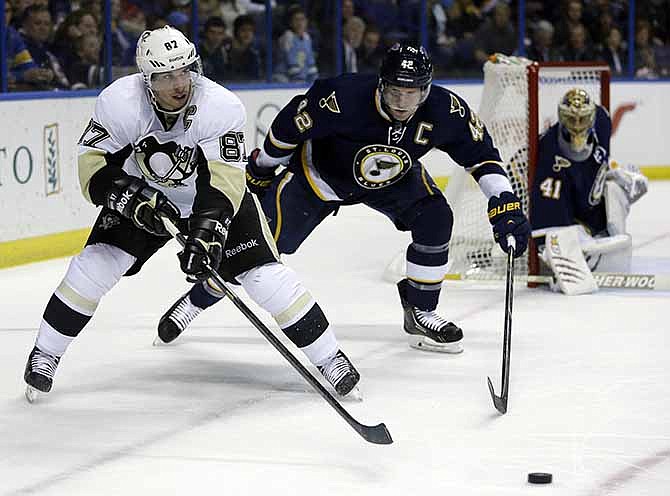Pittsburgh Penguins' Sidney Crosby, left, passes the puck as St. Louis Blues goalie Jaroslav Halak (41), of Slovakia, and David Backes, center, watch during the third period of an NHL hockey game on Saturday, Nov. 9, 2013, in St. Louis. The Blues won 2-1. 