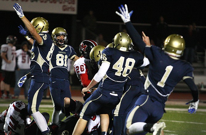 The Helias Crusaders celebrate after a big play just before halftime of their game against Marshall in the first round of districts at Adkins Stadium. Helias will host Hannibal tonight in the district championship game.