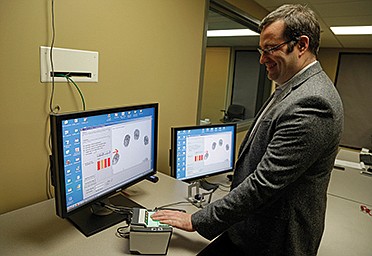 Stephen Elliott, director of International Biometric Research at Purdue University demonstrates a fingerprint recognition system Tuesday at one of his biometric labs in West Lafayette, Ind. Automated recognition of individuals based on their unique behavioral and biological characteristics is going mainstream and being studied by Elliott.