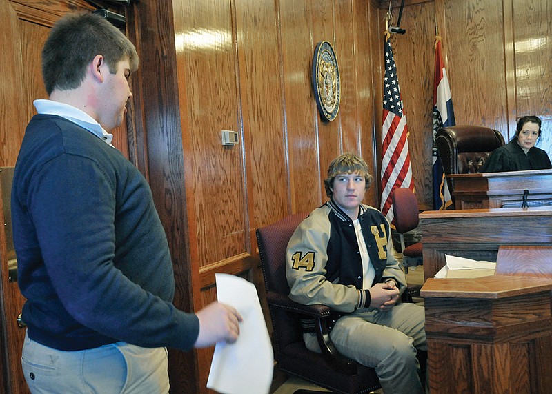 Judge Pat Joyce listens as Helias High School senior Adam Bexten, at left, serves as prosecutor and questions Ben Davis whose role was that of chief detective investigating a single car accident. Helias students competed against Rock Bridge in Tuesday's mock trials.