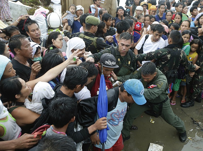 Typhoon survivors jostle to get a chance to board a C-130 military transport plane Tuesday, in Tacloban, central Philippines. Thousands of typhoon survivors swarmed the airport on Tuesday seeking a flight out, but only a few hundred made it, leaving behind a shattered, rain-lashed city short of food and water and littered with countless bodies.