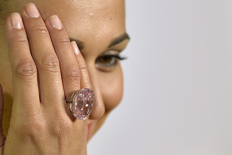 A Sotheby's employee displays "The Pink Star" diamond weighing 59.6 carat, during a preview at Sotheby's, in Geneva, Switzerland. The enormous diamond has sold for $83.425 million at an auction far surpassing its expected price. 