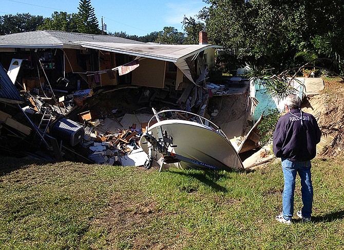 A man observes a sinkhole that has swallowed parts of two houses in Dunedin, Fla. Deputy Fire Chief Trip Barrs said the hole appeared to be about 12-feet wide when officials arrived on the scene. Residents of the neighboring houses also were evacuated as a precaution.  