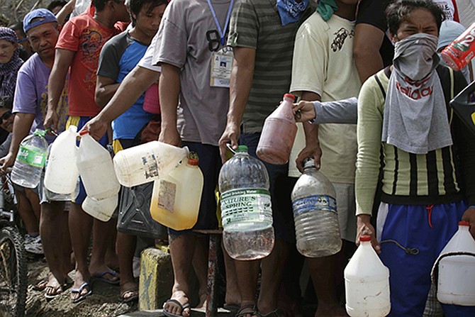Typhoon survivors line up to get fuel from an abandoned filling station Thursday, in Tacloban city, Leyte province in central Philippines. Aid has been slow to reach the half-million people displaced by the storm that tore across several islands in eastern Philippines last Friday. 
