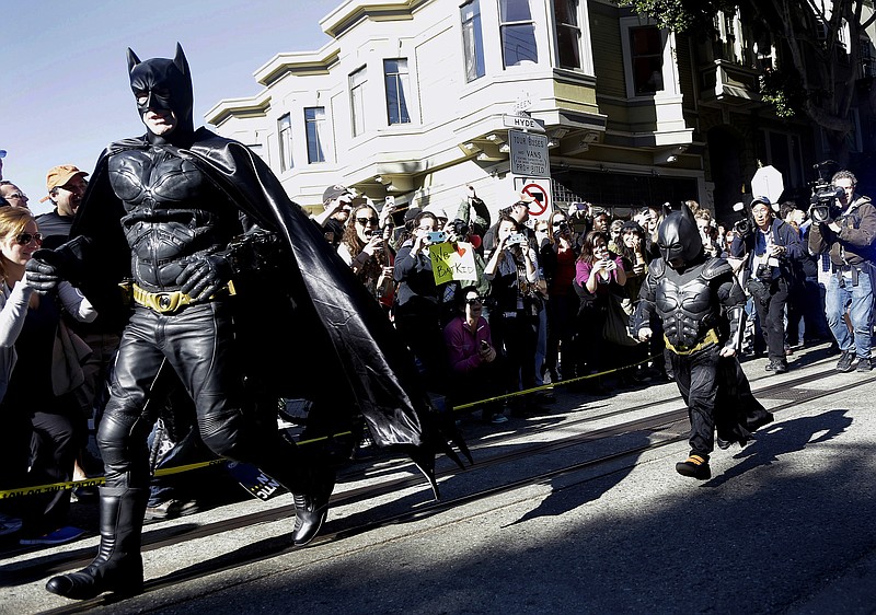 Miles Scott, dressed as Batkid, right, runs with Batman after saving a damsel in distress Friday in San Francisco. San Francisco turned into Gotham City on Friday, as city officials helped fulfill Scott's wish to be "Batkid." Scott, a leukemia patient from Tulelake in far Northern California, was called into service on Friday morning by San Francisco Police Chief Greg Suhr to help fight crime, The Greater Bay Area Make-A-Wish Foundation says.