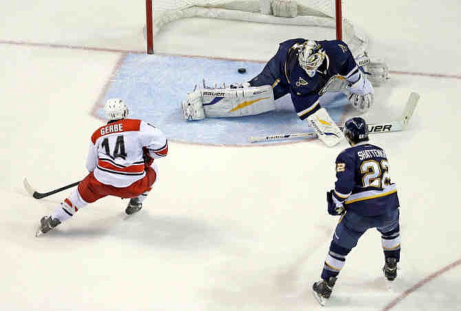 Carolina Hurricanes' Nathan Gerbe (14) scores past St. Louis Blues goalie Brian Elliott and Kevin Shattenkirk (22) during the second period of an NHL hockey game Saturday, Nov. 16, 2013, in St. Louis.