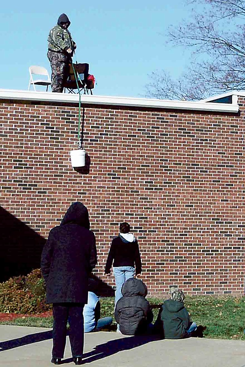 Democrat Photo/Paula Earls
Principal Daniel Williams lowers books in a bucket to California fifth grade students after he read to them.  Each class at California came outside with books to hoist up for him to read from the rooftop as part of the Principal's Challenge.