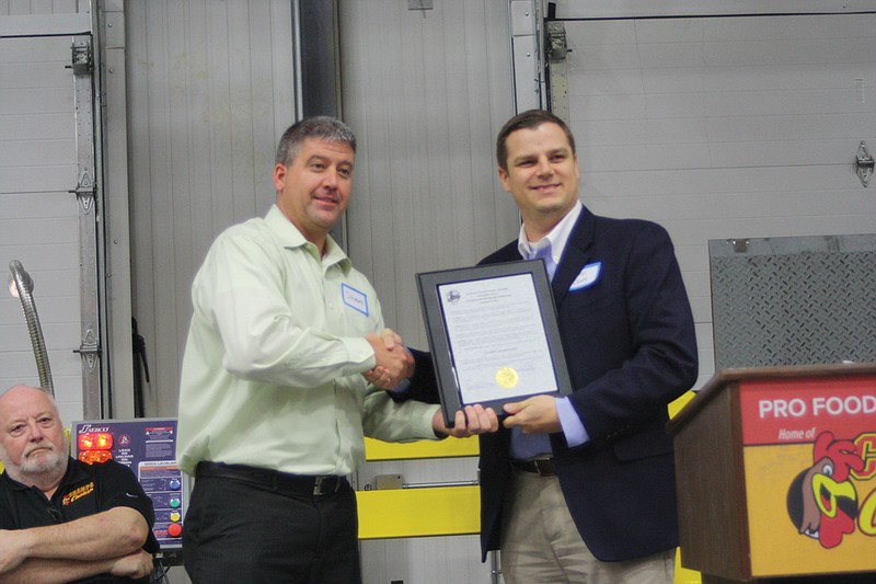 Holts Summit City Administrator Brian Crane, right, presents Pro Food Systems CEO Shawn Burcham with a proclamation declaring Nov. 19 "Champs Chicken Day." City and state officials were among many helping the firm celebrate its $6 million expansion, which will create 43 new jobs over three years.
