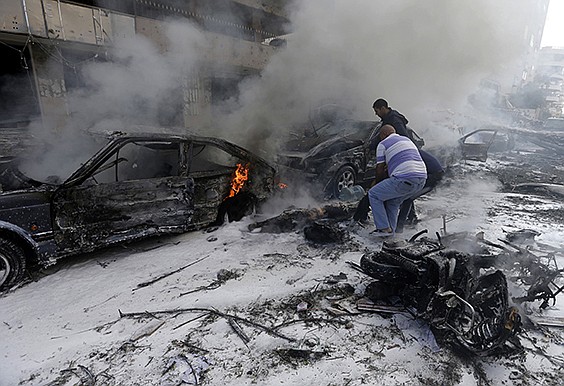 Two Lebanese men remove a dead body from a burned car, at the scene where two explosions have struck near the Iranian Embassy killing many, in Beirut, Lebanon. The blasts in south Beirut's neighborhood of Janah also caused extensive damage on the nearby buildings and the Iranian mission.