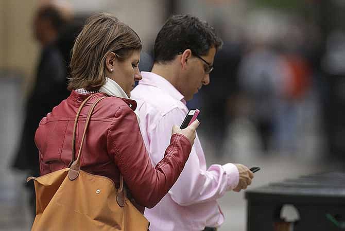 In this June 5, 2013, file photo, people use cellphones in downtown San Francisco. 