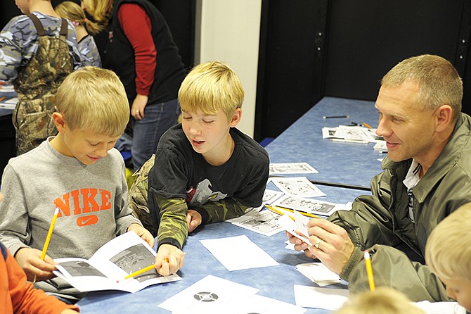 Cameron Larimore and Carter Epema search for words at a Literacy Night activity Tuesday at Cole County R-1 Elementary School, while Michael Larimore listens in. 