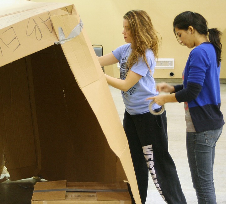 Rachael Holloway, fellow for Community Service, uses duct tape to hold together her cardboard house on Nov. 21 while Tripit Giri looks on and advises her. The Westminster community gathered to go through a Cardboard City simulation for Poverty Awareness Week. Elyssa Mann/FULTON SUN