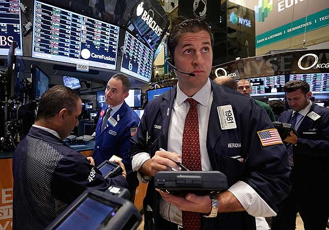 In this Tuesday, Nov. 19, 2013, file photo, Trader Thomas Donato, center, works on the floor of the New York Stock Exchange. Global stock markets, except Japan, were in the red Thursday Nov. 21, 2013 amid jitters over new signals from the U.S. Federal Reserve that it may cut monetary stimulus sooner than expected.