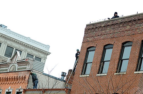 Mike Baugher, left; Steven Ashby, on ladder; and Brandon Russell string lights across the tops of buildings Friday on the north side of High Street. They are part of a crew from Shepherd's Company that has been busy this week climbing ladders and crawling along ledges in downtown Jefferson City to string up lights for the Christmas season.
