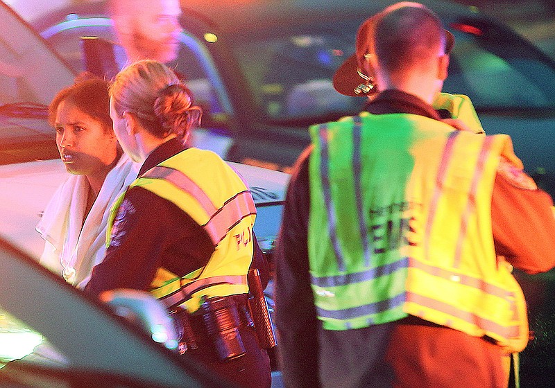 Police lead Marion Guerrido. left, to an ambulance Nov. 21 after the car she was driving with five children veered off a Minneapolis suburban Minneapolis highway ramp and became submerged in a storm water pond. Authorities said Friday that two of the five children trapped in the car have died. Guerrido, the 23-year-old mother of three of the children, escaped and screamed for help, according to authorities.
