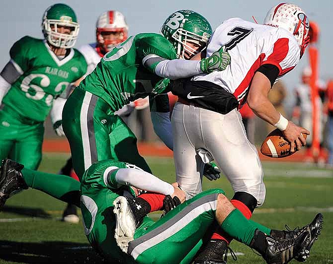 Blair Oaks' Chance Cumpton (79) lays a hit on Lawson quarterback Garrett Titus as Hayden Haney (50) of the Falcons wraps up his legs during Saturday's Class 2 semifinal game at the Falcon Athletic Complex in Wardsville.