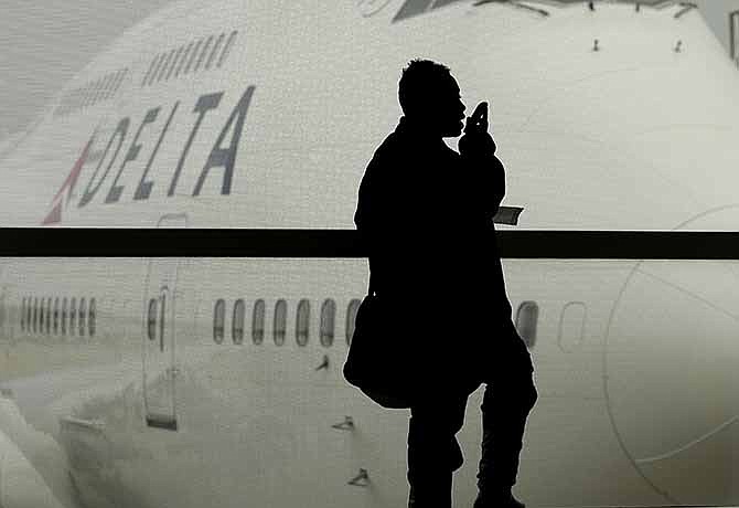 In this Oct. 29, 2012, file photo, a traveler on Delta Airlines waits for her flight in Detroit. For the past decade fliers haven't been able to use electronic devices while planes are below 10,000 feet because they might interfere with cockpit instrument, but the Federal Aviation Administration declared Thursday Nov. 21, 2013, that interference isn't a concern anymore. 