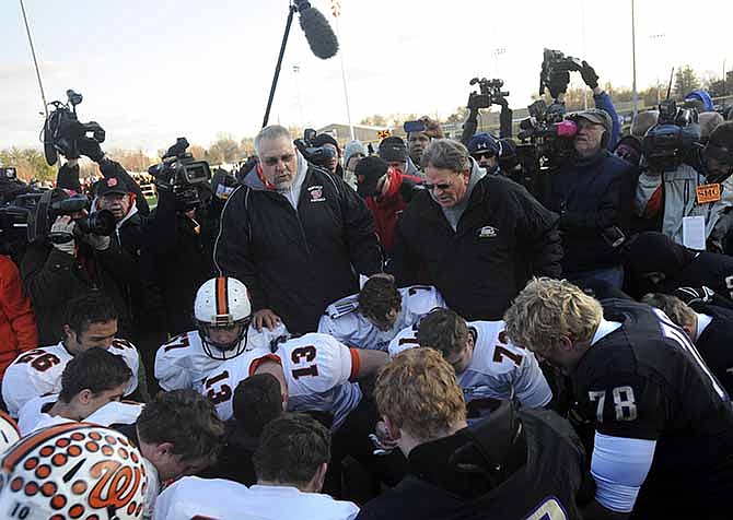 Washington High School head coach Darrell Crouch, left, and Sacred Heart-Griffin head coach Ken Leonard, say a prayer with football players from both Illinois teams Saturday Nov. 23, 2013, after a Class 5A football semifinal playoff game in Springfield, Ill. Washington lost the game, 44-14, but still played the game despite over 10 players on the roster that lost their family home after a tornado tore throughout central Illinois town last Sunday.