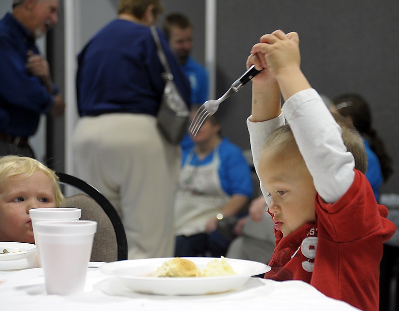 Jace Espinales, 2, goes in for the kill on his turkey dinner, apparently unaware that the bird can no longer fly away from his plate. The Eugene boy was among the dozens of area residents, inset below, who came to Eugene Christian Church's second annual community Thanksgiving dinner Sunday evening.
