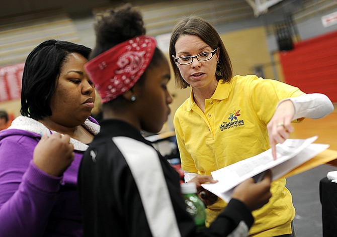 Simonsen physics teacher Karen Pullen, right, goes over a list of required courses with Thomas Jefferson Middle School 8th grader Denae Purtty, center, and her mom Meketa Clark as they visit the Human Services Academy booth during Monday evening's Academy Jamboree at Jefferson City High School. The event was hosted to give prospective students and parents the opportunity to learn what each of the seven JCHS academies will offer.