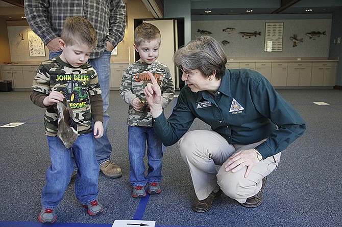 Anne Hutton, a volunteer with the Runge Nature Center, helps twins Grant and Connor Carender, 2, follow the maze to identify the species of duck to which their wings belonged to Friday morning. 