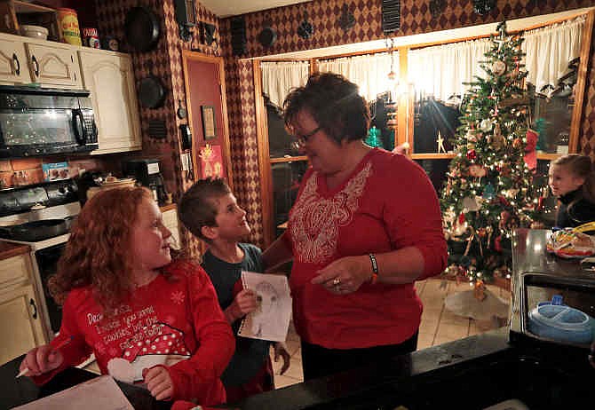 Triplets, from left to right, Addison, Maddox and Addison Waller-Brenneke, create their lists for Santa Claus with the help of Cheryl Rawson-Brenneke after dinner on Monday, Nov. 25, 2013, in Ste. Genevieve County, Mo. Rawson-Brenneke is the older sister of Jacque Waller, the mother of 5-year-old triplets, who was killed by her estranged husband in 2011. Her body was finally found in May and her husband, Clay Waller, is serving a 20-year prison sentence. Rawson-Brenneke and her husband, Bob Brenneke,, took in the triplets, now 8, and their adoption was finalized earlier this month. (AP Photo/St. Louis Post-Dispatch, Laurie Skrivan) 