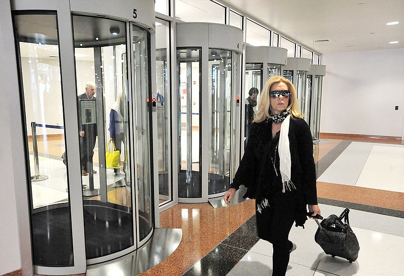 Passenger Laura West, of Red Bank, N.J., walks past security portals at the completed $27M terminal expansion project at the Atlantic City International Airport in Egg Harbor Township, N.J.  The doors are designed to keep people from coming back through exits to secure areas, and to keep the TSA from posting a guard at such exits.