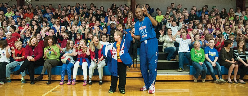 South Callaway student Denver Summers smiles at the crowd during an assembly after Harlem Swish member Valentino Willis lets Summers wear his basketball jacket.
