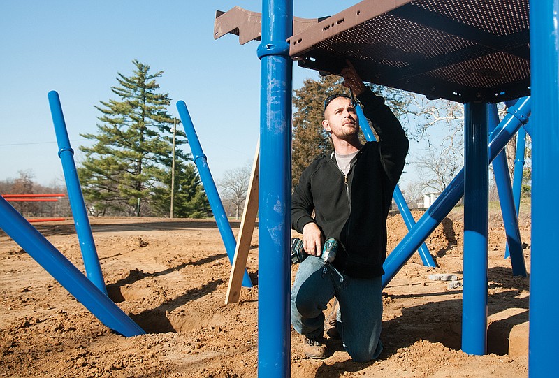 Andy Nash, employee with the playground construction company Miracle Recreation, tightens a bolt on new playground equipment at Veterans Park in Fulton on Wednesday. The new playground will include two slides and climbing bars as well as two swing sets that feature tire swings, regular swings and gliders.