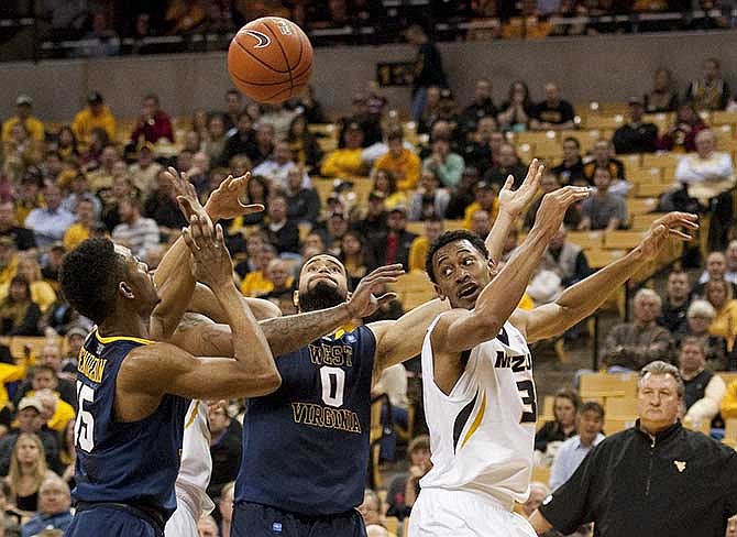 West Virginia's Terry Henderson, left, Remi Dibo, center, and Missouri's Johnathan Williams III, right, battle for a rebound during the first half of an NCAA college basketball game Thursday, Dec. 5, 2013, in Columbia, Mo.