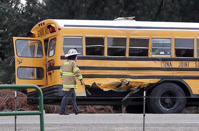 A firefighter walks past the damaged Kuna School District bus at the scene of a fatal crash on Thursday in Kuna, Idaho. Authorities say one child has died and five people were injured, including four children, when a dump truck collided with the school bus carrying elementary school students.