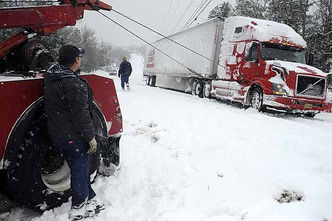Jim Dobbs, left, helps pull a tractor trailer rig out of a ditch Friday, Dec. 6, 2013, in Henderson, Ark. The icy storm plowing across the country is delaying shipments of everything from Christmas presents to cooking grease.